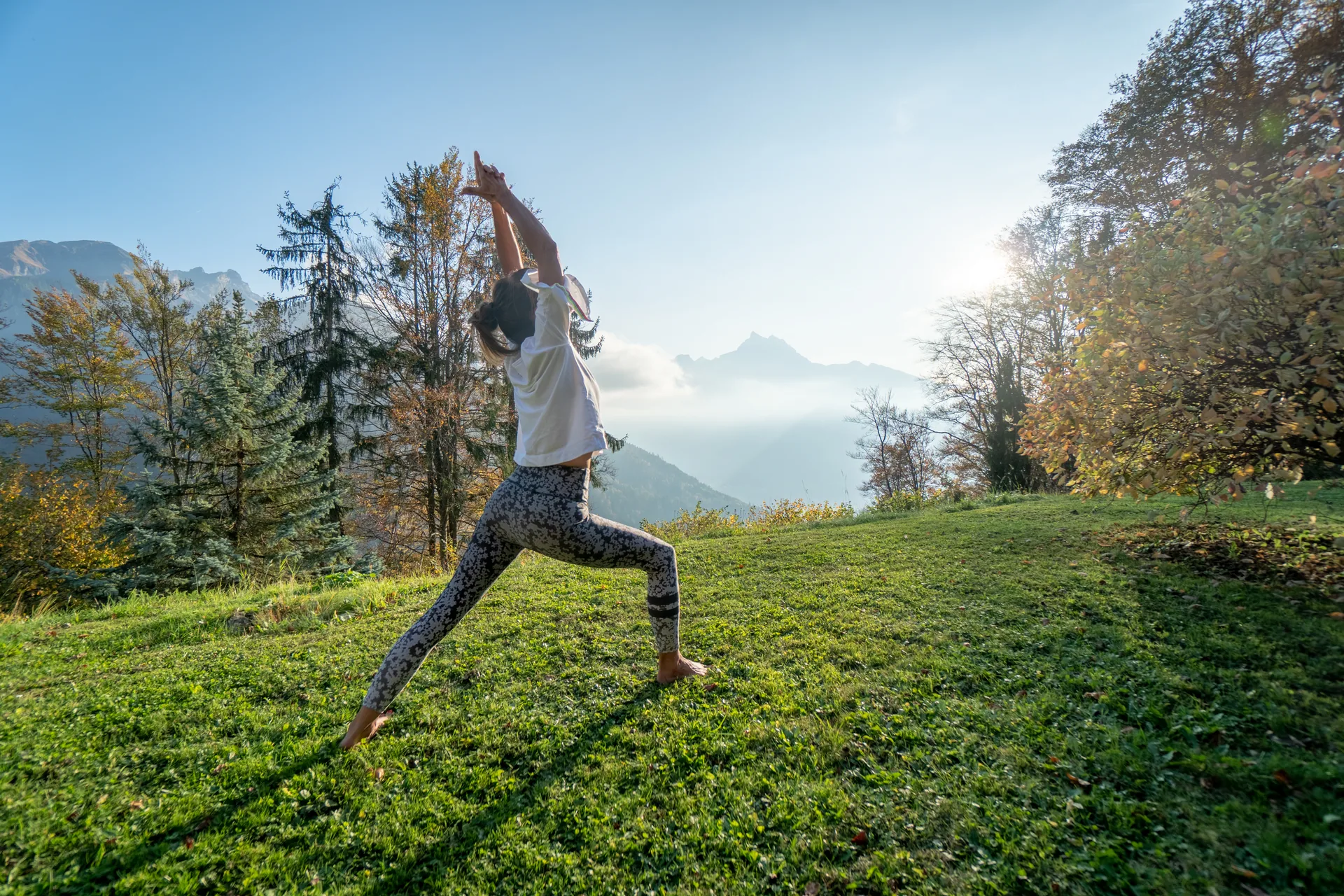 Bernadette en posture de yoga, face aux montagnes au lever du soleil
